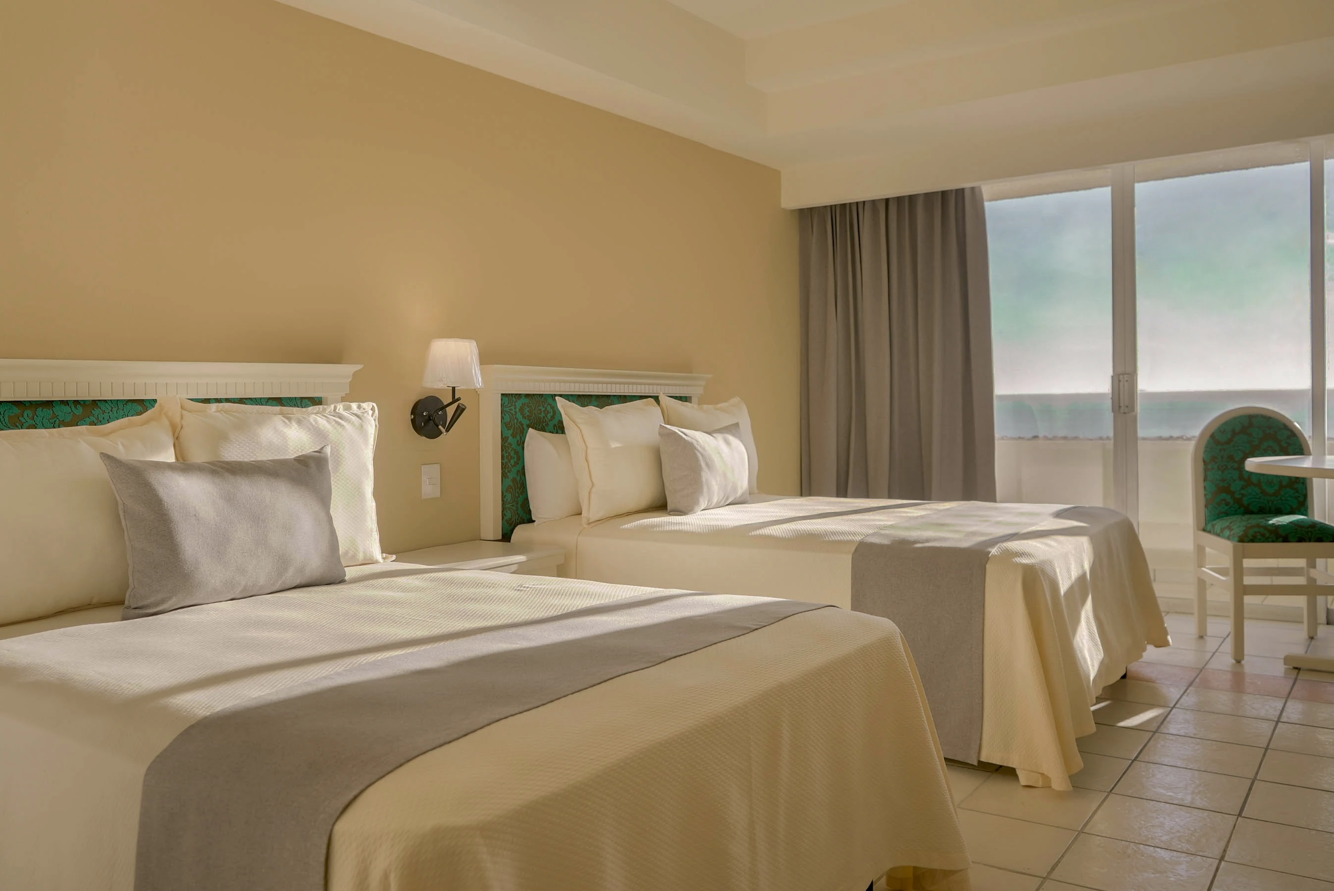Habitación standar con balcón y vista al mar, dos camas matrimoniales, mesa con dos sillas del hotel oceano palace Mazatlán